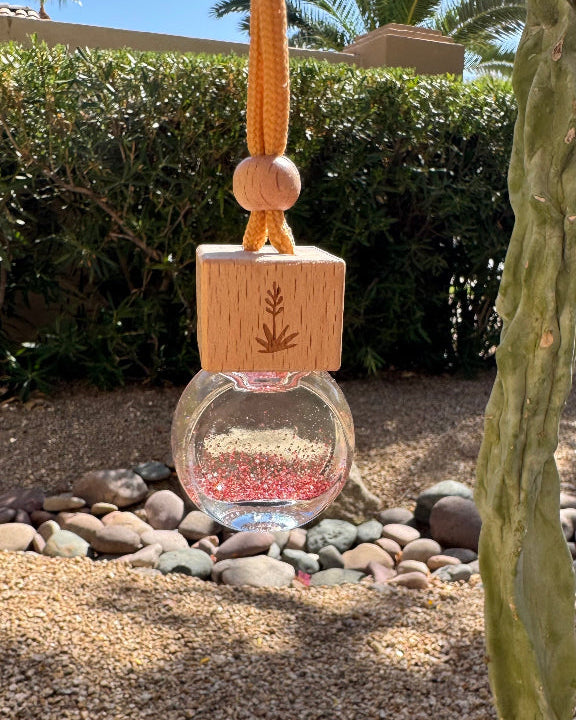 Arizona Sunset 8 mL hanging car diffuser with pink and gold glitter, engraved wooden lid, and orange cord.