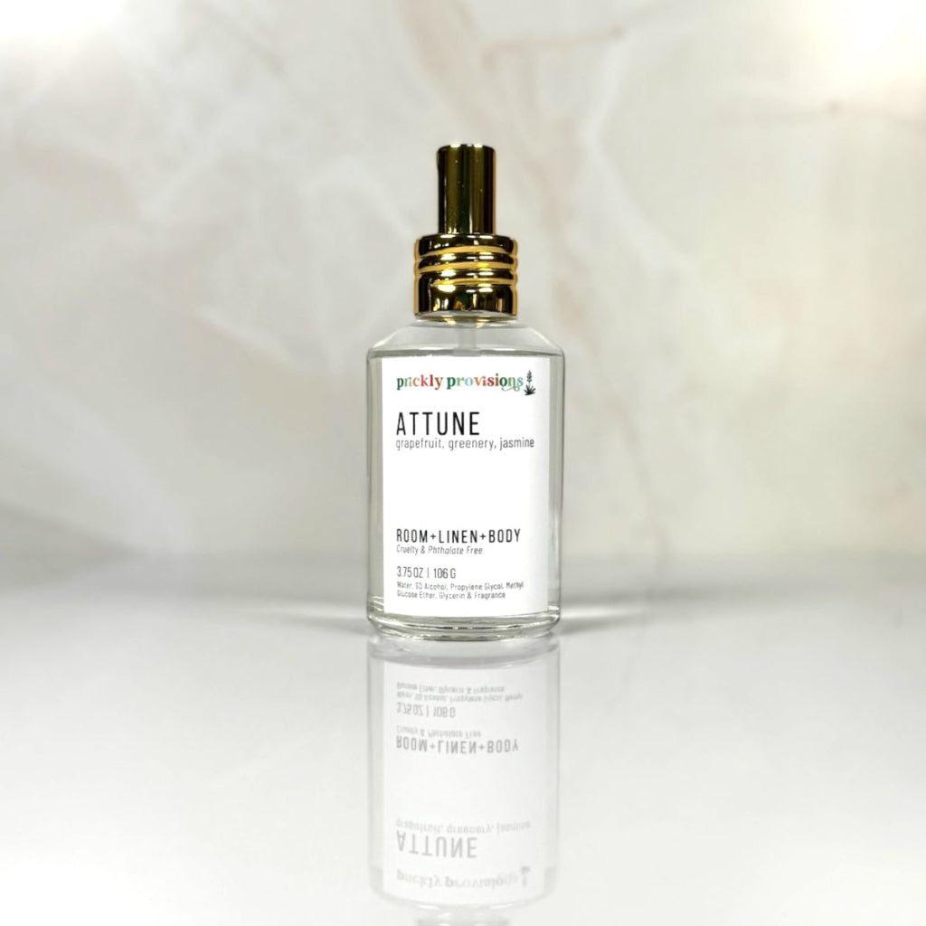 Attune 4 oz room, linen, and body spray in a clear glass bottle with a polished gold sprayer.