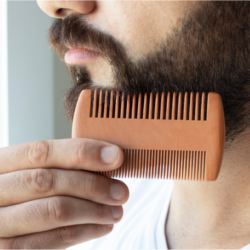 Man holding a wooden comb near his beard