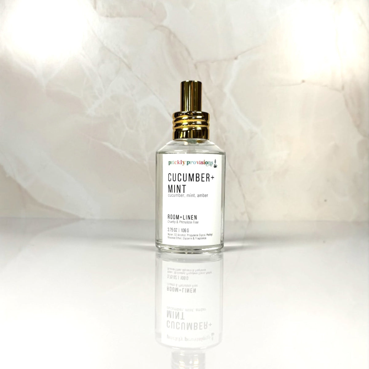 Cucumber + Mint 4 oz room and linen spray in a clear glass bottle with a polished gold sprayer.