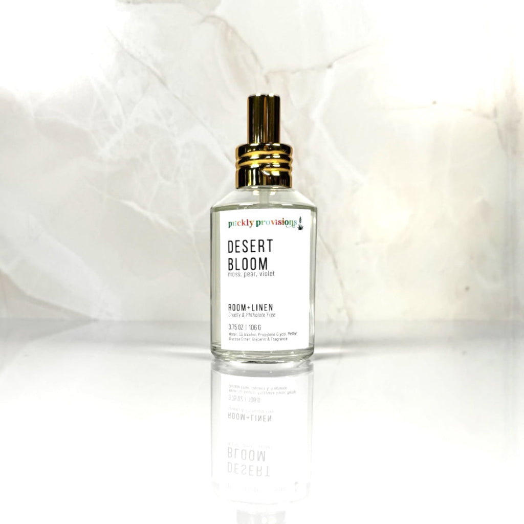 Desert Bloom 4 oz room and linen spray in a clear glass bottle with a polished gold sprayer.