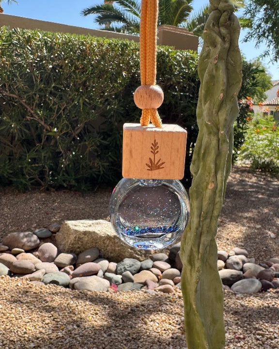 Goddess 8 mL hanging car diffuser with blue iridescent glitter, engraved wooden lid, and orange cord.