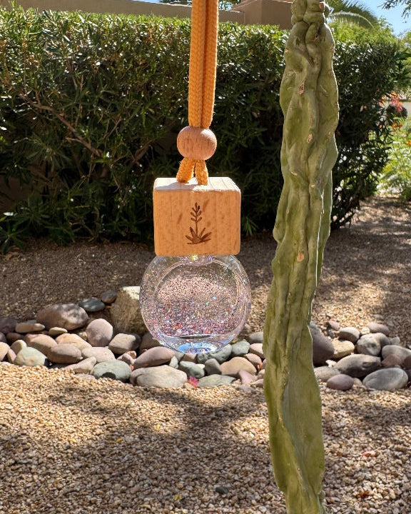 Sea Salt + Orchid 8 mL hanging car diffuser with iridescent glitter, engraved wooden lid, and orange cord.