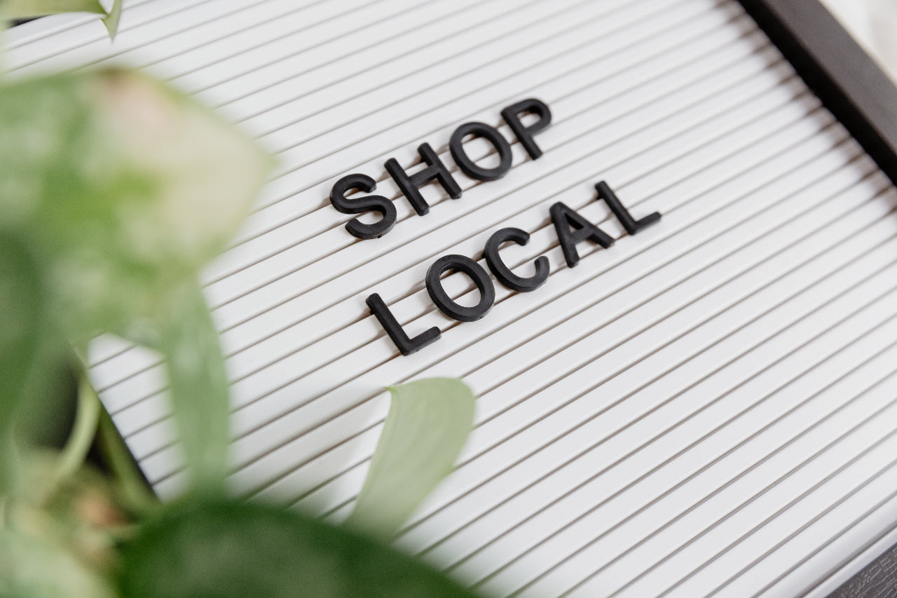 Shop Local sign board with some plant leaves