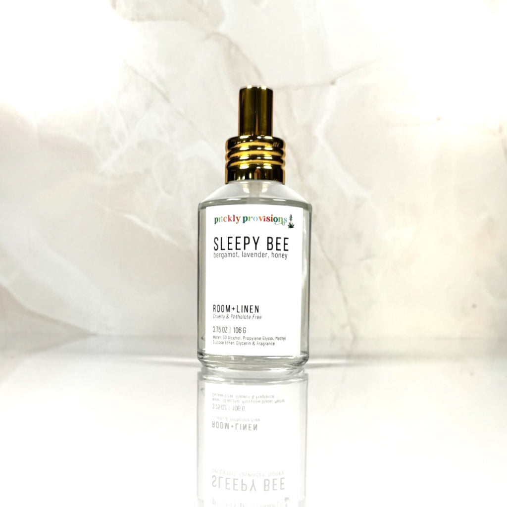 Sleepy Bee 4 oz room and linen spray in a clear glass bottle with a polished gold sprayer.