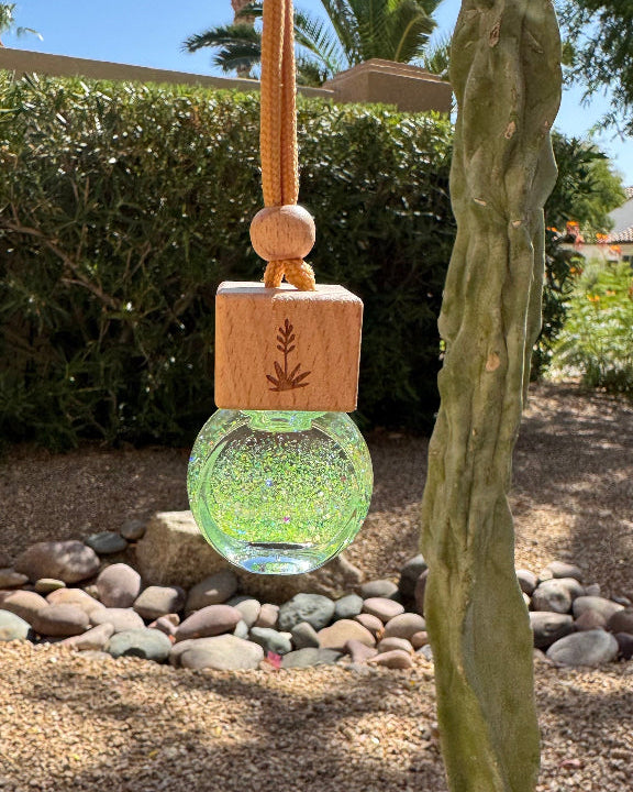 Sonoran Desert 8 mL hanging car diffuser with iridescent green glitter, engraved wooden lid, and orange cord.