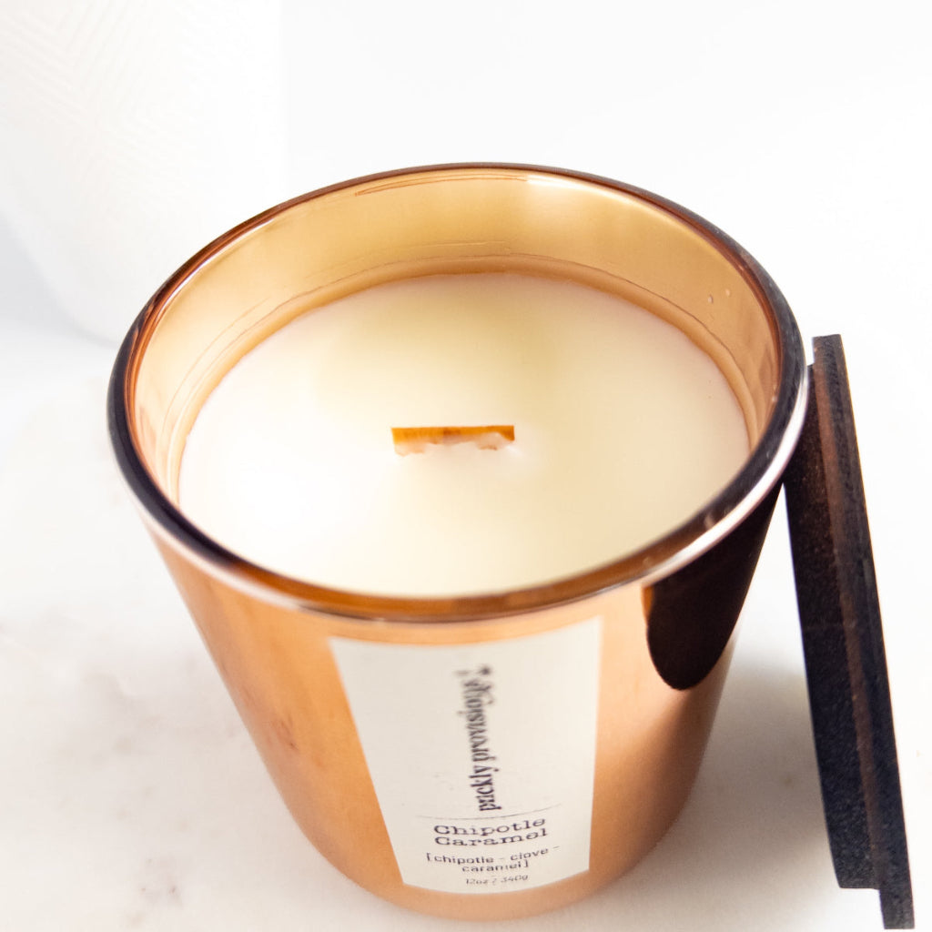 Chipotle Caramel 12 oz wood-wick candle in a lustrous copper glass vessel with coordinating wood lid.