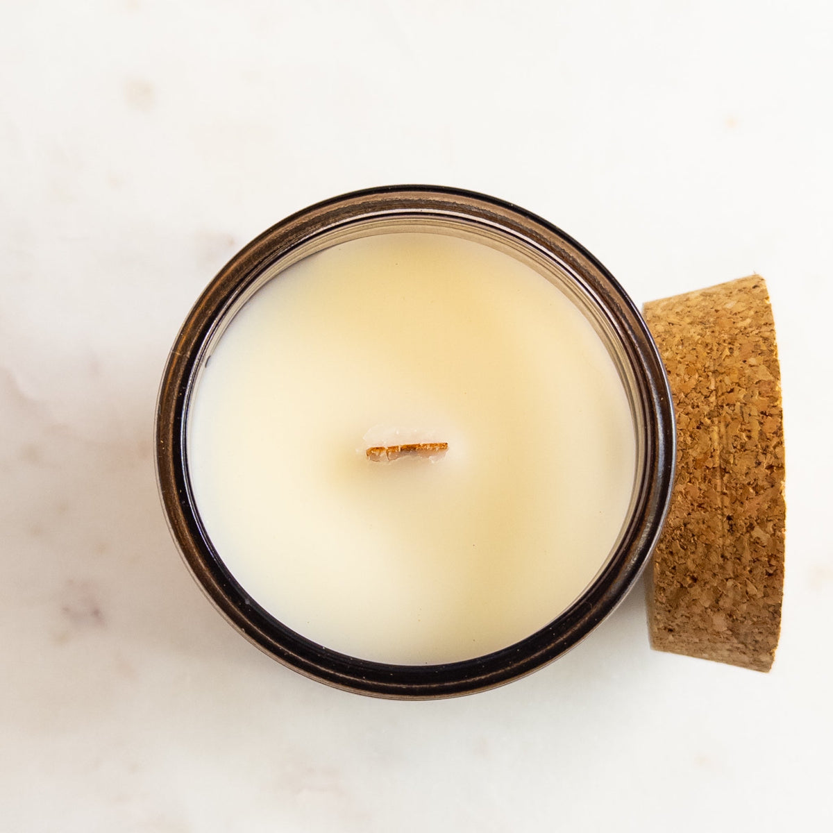 Candle in a glass jar with a cork lid on a light background