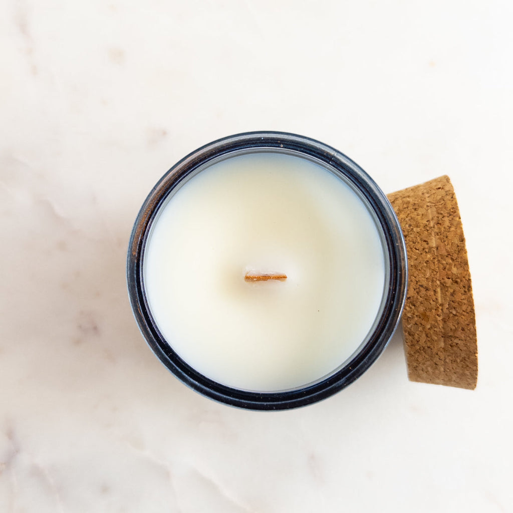 Grounded 7.5 oz wood-wick candle in a recycled-glass vessel.