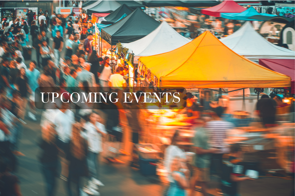 Blurred image of a bustling outdoor market with tents and people, featuring text 'UPCOMING EVENTS'.