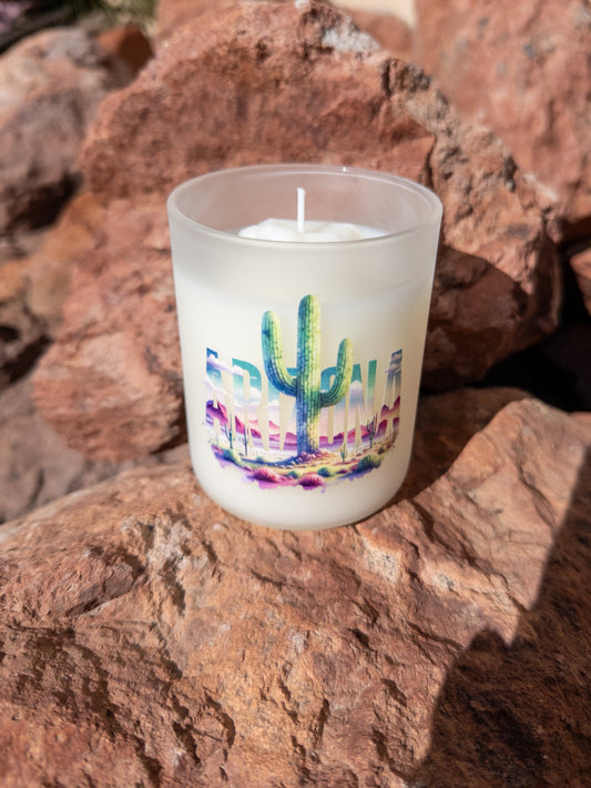 Candle with a colorful cactus design on a rock surface