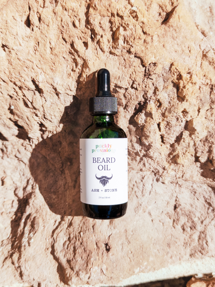 Bottle of beard oil with a dropper on a textured stone background