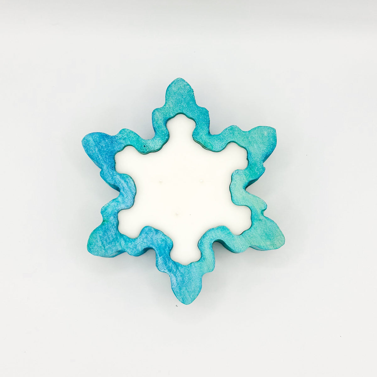 A snowflake shaped blue stained wooden dough bowl candle with 3 wicks