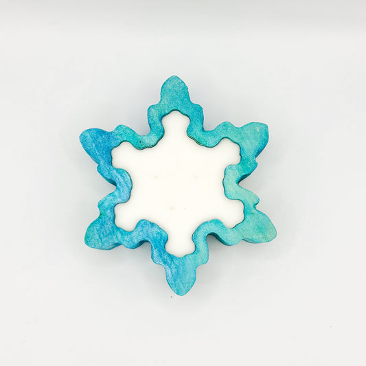 A snowflake shaped blue stained wooden dough bowl candle with 3 wicks