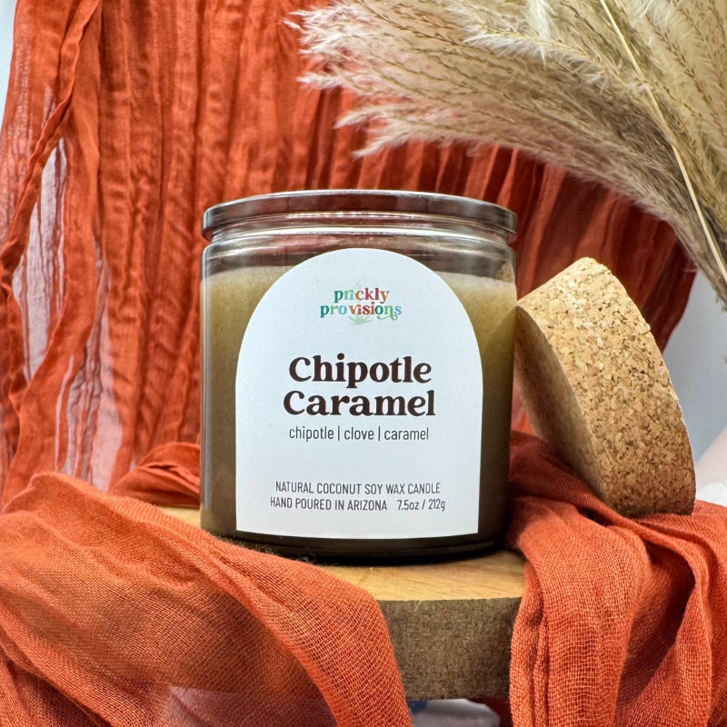 Candle labeled 'Chipotle Caramel' by Prickly Provisions on an orange fabric background.