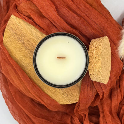 White candle in a wooden holder on a rust-colored fabric background