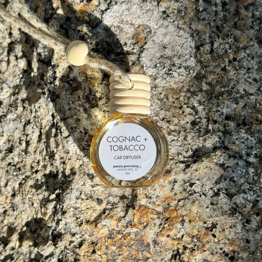 Cognac and tobacco-scented car diffuser on a textured stone surface