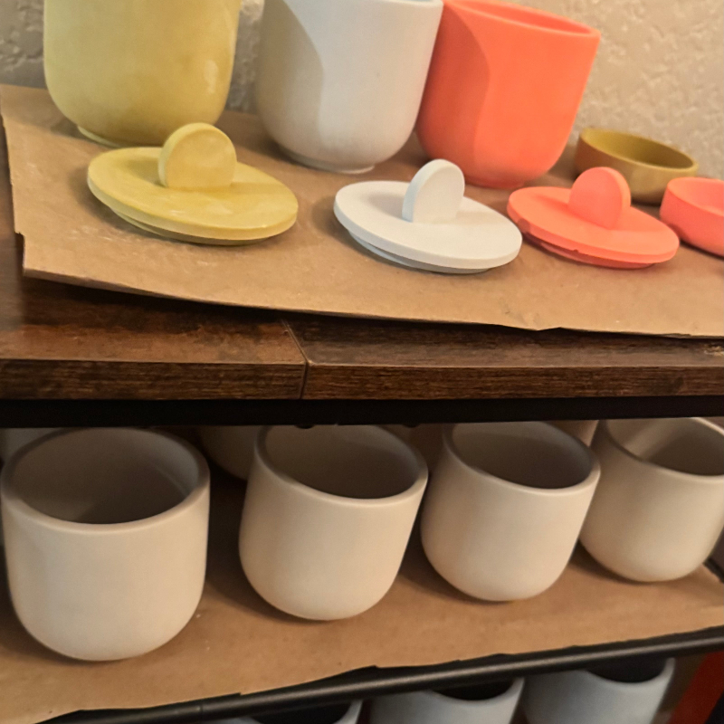 Collection of concrete candle jars and lids on a wooden shelf.
