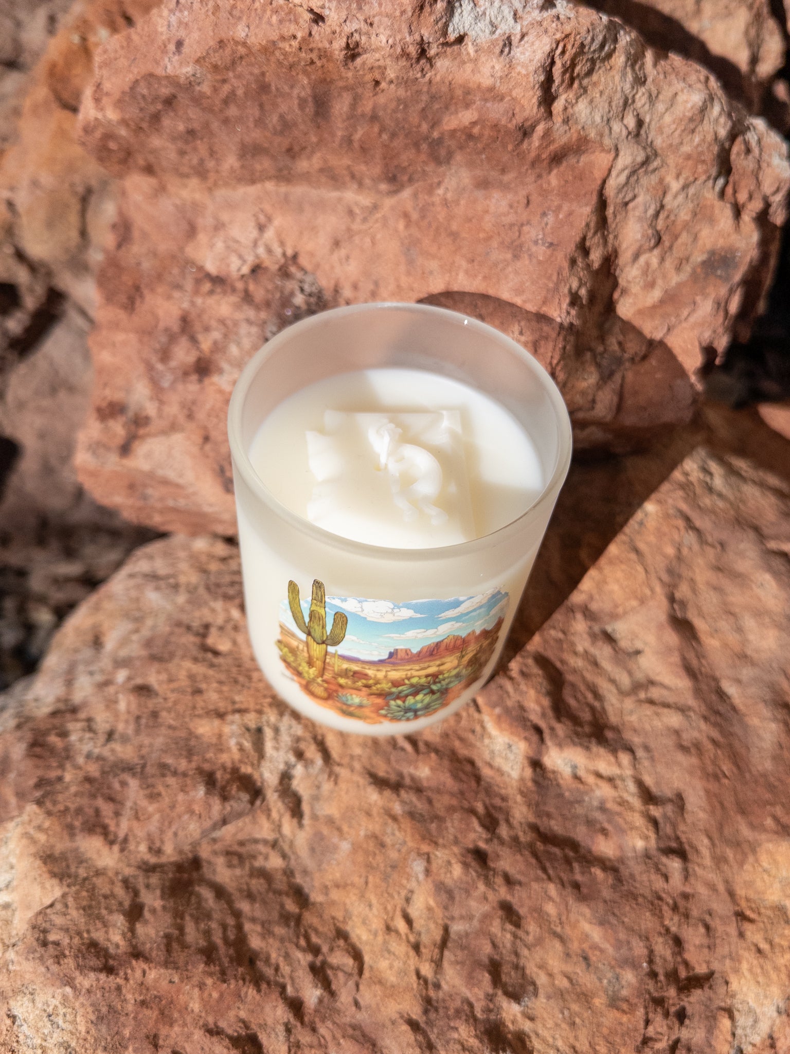 Candle with a desert-themed label on a rocky surface