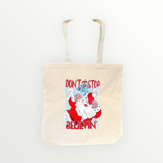Tote bag with Santa Claus graphic and text 'Don't Stop Believin'' on a white background