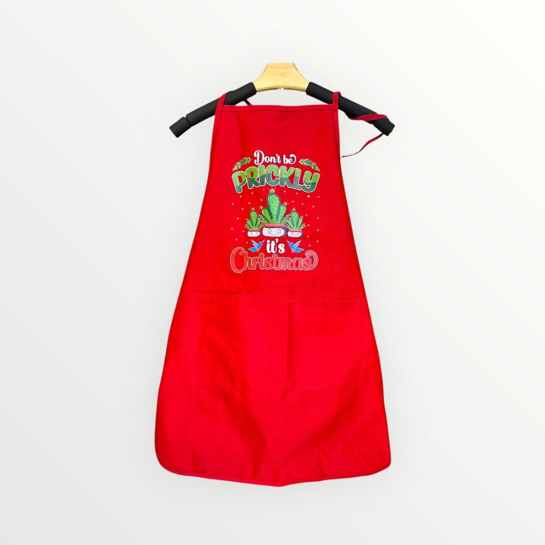 Red apron with Christmas-themed text and cactus graphics on a white background