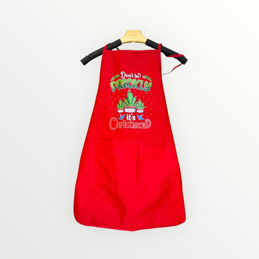Red apron with Christmas-themed text and cactus graphics on a white background