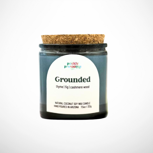 Candle jar with cork lid labeled 'Grounded' by Prickly Provisions on a white background