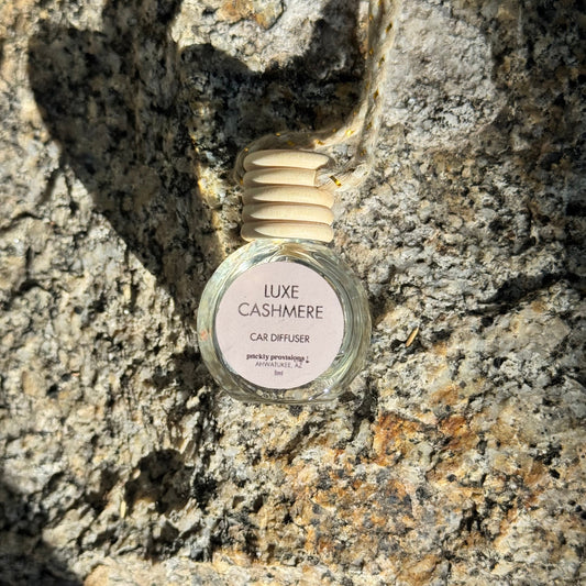 Luxe Cashmere car diffuser bottle on a textured stone surface