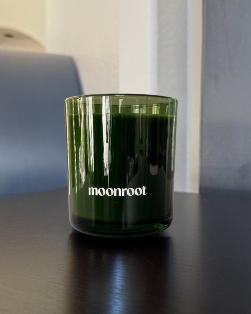 Moonroot candle in a translucent deep green glass vessel