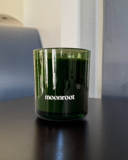 Moonroot candle in a translucent deep green glass vessel