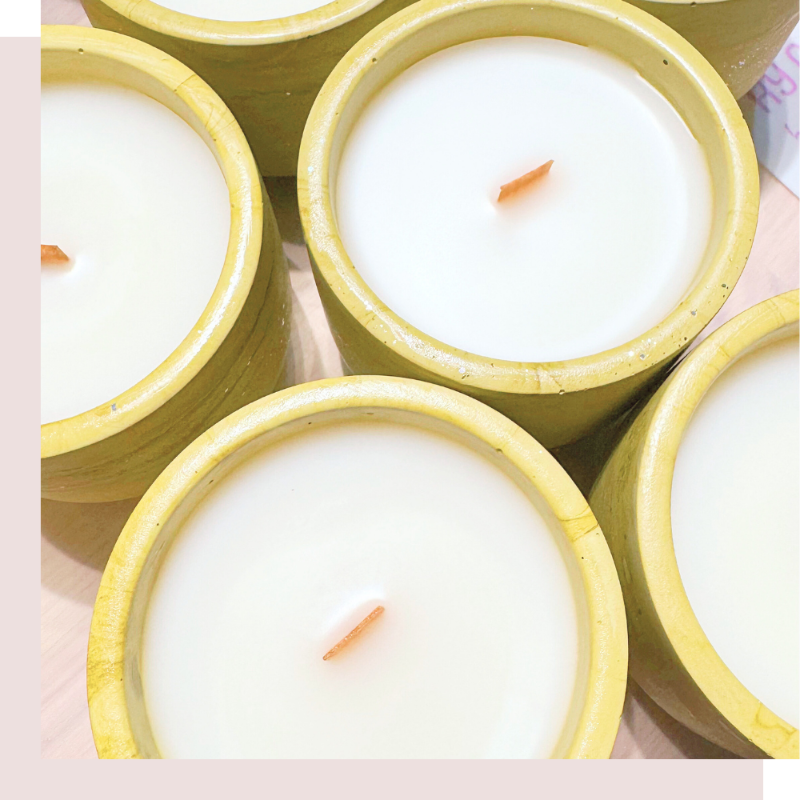 Candles in concrete cement green yellow holders on a pink background
