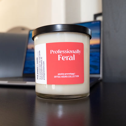 Professionally Feral 10 oz double-wick office candle with a coral-red label and black metal lid.