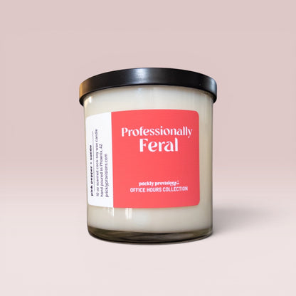 Professionally Feral 10 oz double-wick office candle with a coral-red label and black metal lid.