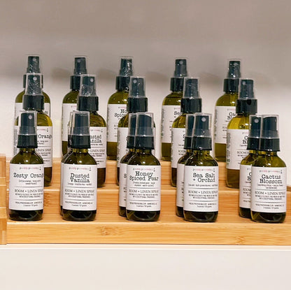Row of small bottles with labels on a wooden shelf against a neutral background