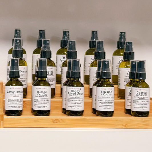 Row of small bottles with labels on a wooden shelf against a neutral background