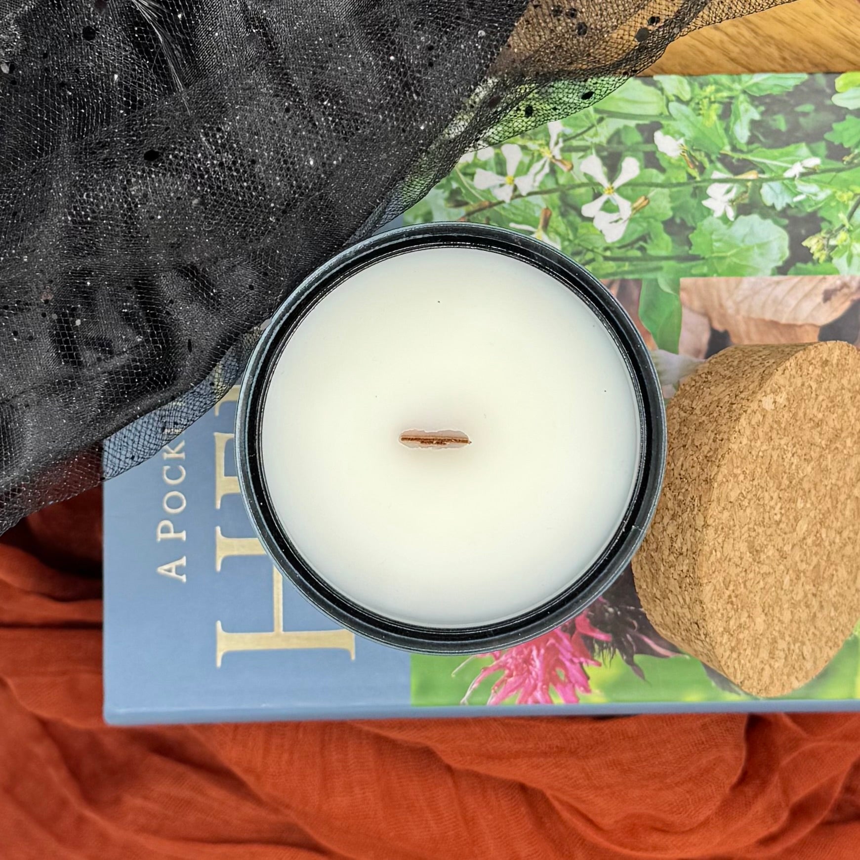 Candle in a glass jar on a book with a decorative background