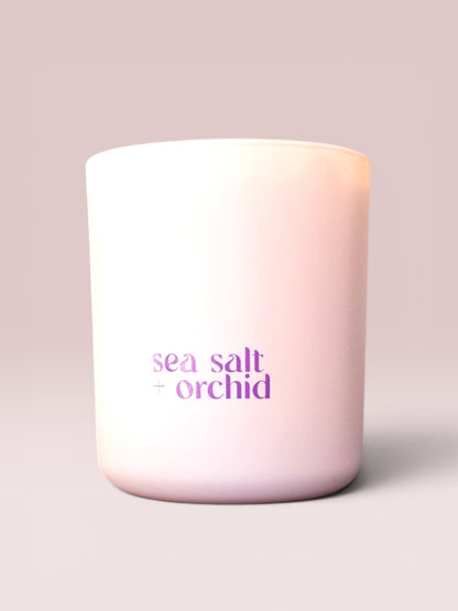 Candle with 'sea salt orchid' text on a light pink background