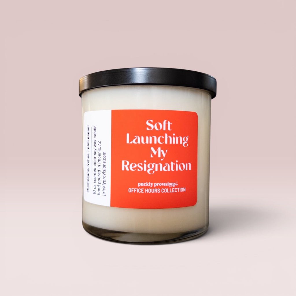 Soft Launching My Resignation 10 oz double-wick office candle with an orange-red label and black metal lid.