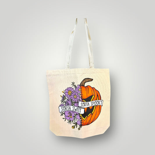 Tote bag with Halloween design featuring a pumpkin and flowers on a light gray background