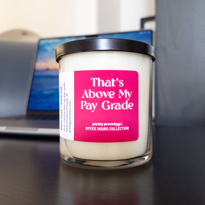 That’s Above My Pay Grade 10 oz double-wick office candle with a bright pink label and black metal lid.