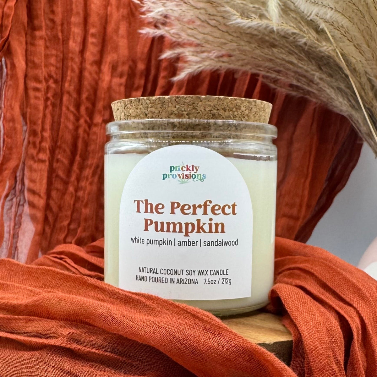 Candle labeled 'The Perfect Pumpkin' by Puckly Provisions on a rustic background