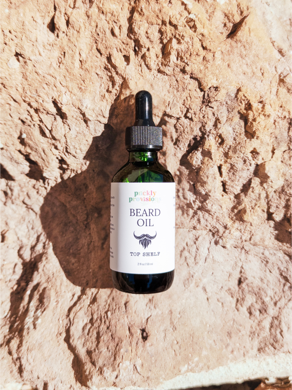 Bottle of beard oil with a dropper on a textured stone background