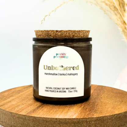 Candle jar with cork lid on a wooden surface, featuring a label with product details.