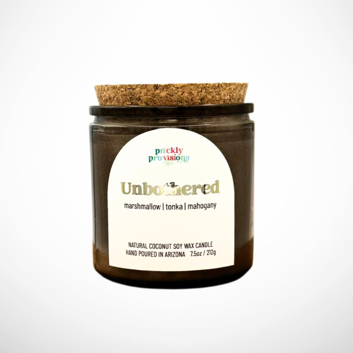 Candle jar with cork lid and 'Unbothered' label on a white background