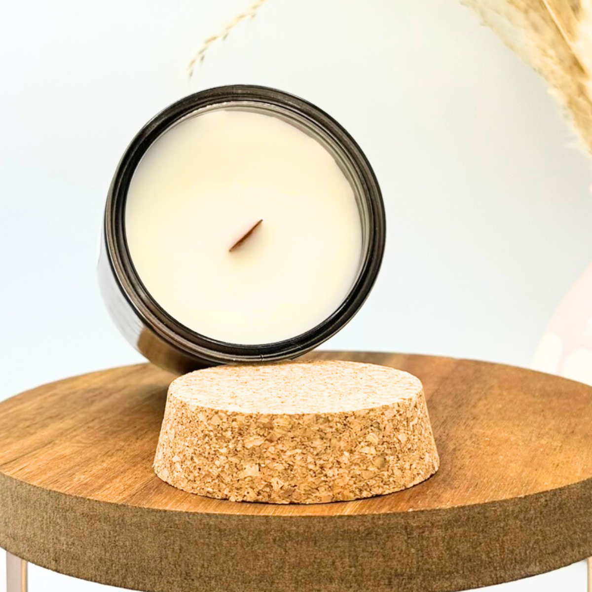 Candle in a recycled glass holder on a cork base with a blurred background