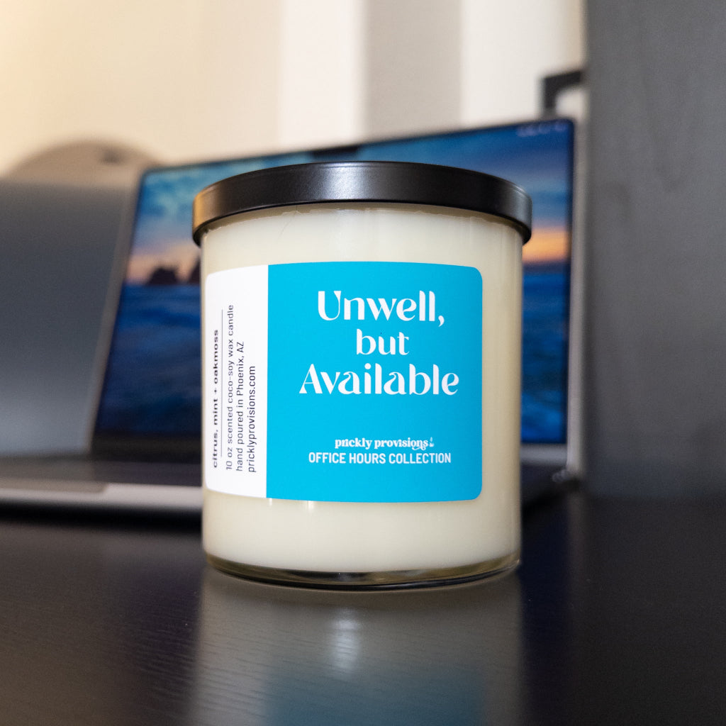 Unwell, But Available 10 oz double-wick office candle with a bright blue label and black metal lid.