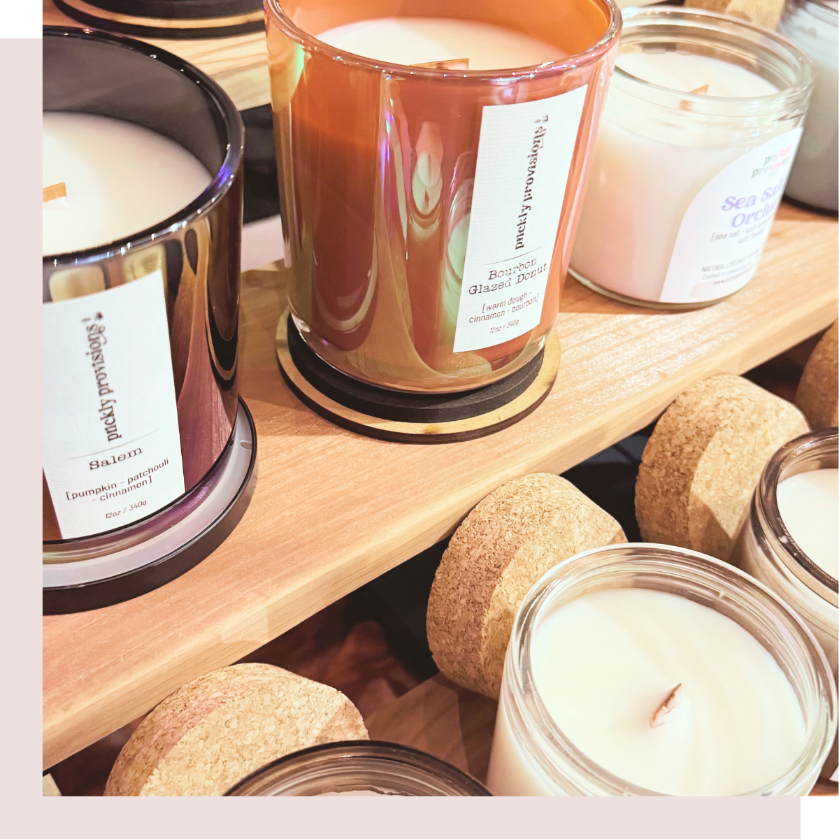Assorted candles on a wooden shelf with visible labels.
