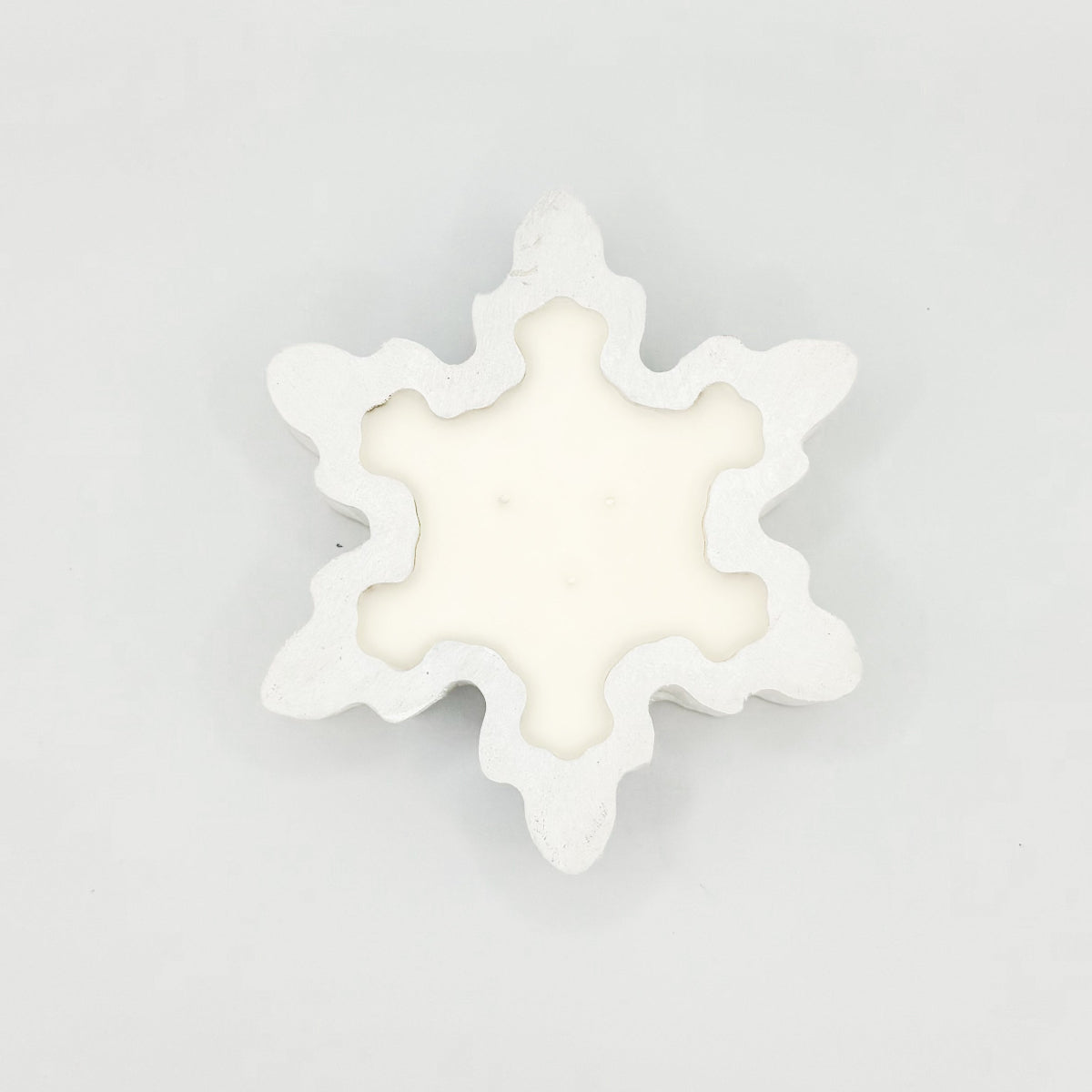A snowflake shaped white wooden dough bowl candle with 3 wicks