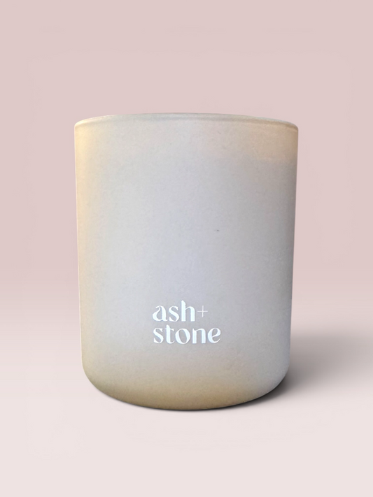 Ash + Stone 10 oz double-wick candle in a matte stone glass vessel.
