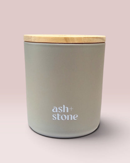 Ash + Stone 9 oz double-wick candle in a matte stone glass vessel.
